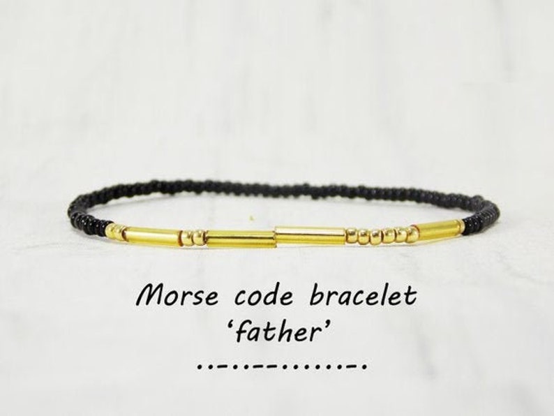May include: Black beaded bracelet with gold beads and bars spelling out the Morse code for 'father'.