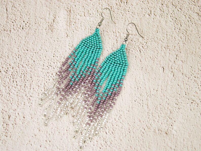 May include: A pair of long, beaded earrings with a gradient of turquoise, purple, and silver beads.