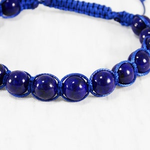 May include: A blue bracelet with dark blue round beads and blue cord.