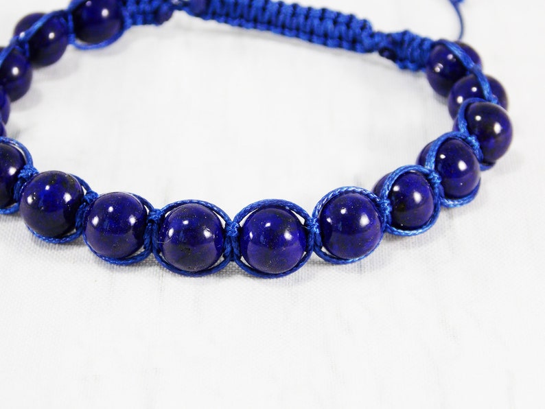 May include: A blue bracelet with dark blue round beads and blue cord.