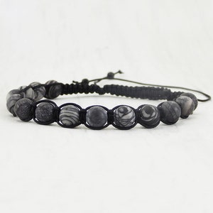 Puede incluir: Un brazalete trenzado negro con cuentas de patrones grises y blancos.