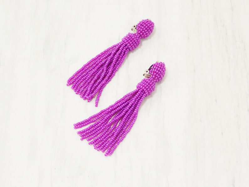 May include: A pair of purple beaded tassel earrings with silver clip-on closures.