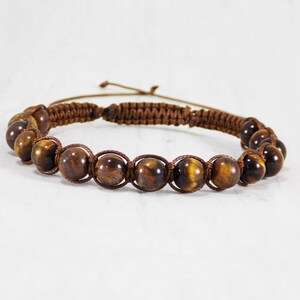 May include: A brown braided cord bracelet with tiger's eye beads.