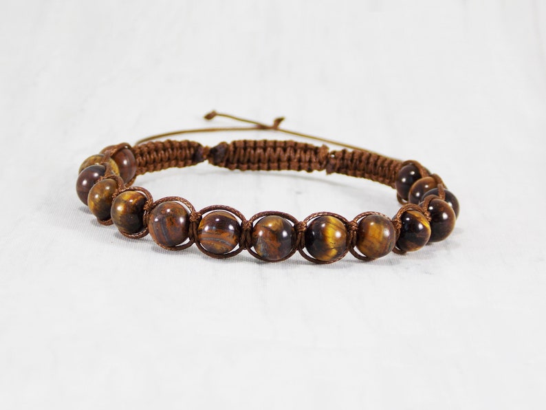 May include: A brown braided cord bracelet with tiger's eye beads.