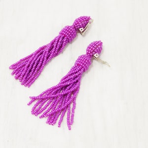 May include: A pair of purple beaded tassel earrings with clip-on closures.