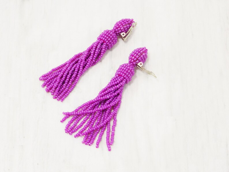 May include: A pair of purple beaded tassel earrings with clip-on closures.