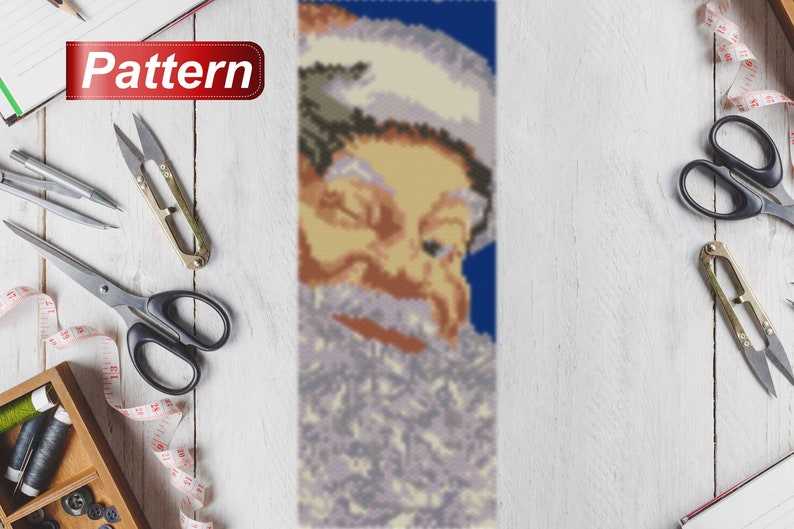 May include: A beaded pattern of Santa Claus's face with a white beard and blue background. The pattern is made with small beads and is suitable for a craft project.