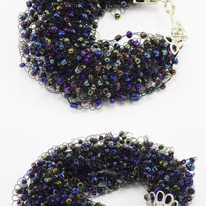 May include: A black crocheted bracelet with iridescent beads in shades of blue, green, and purple. The bracelet has silver metal clasps.