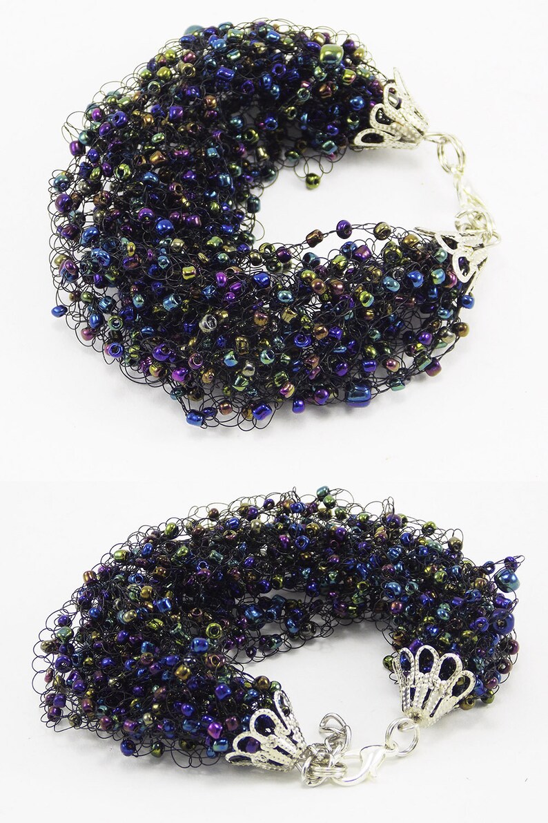 May include: A black crocheted bracelet with iridescent beads in shades of blue, green, and purple. The bracelet has silver metal clasps.