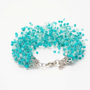 May include: A turquoise and white beaded bracelet with a silver clasp. The beads are clustered together to create a fluffy, cloud-like effect.