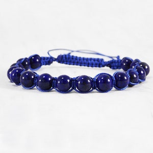 May include: A blue bracelet with dark blue gemstone beads and a blue cord.