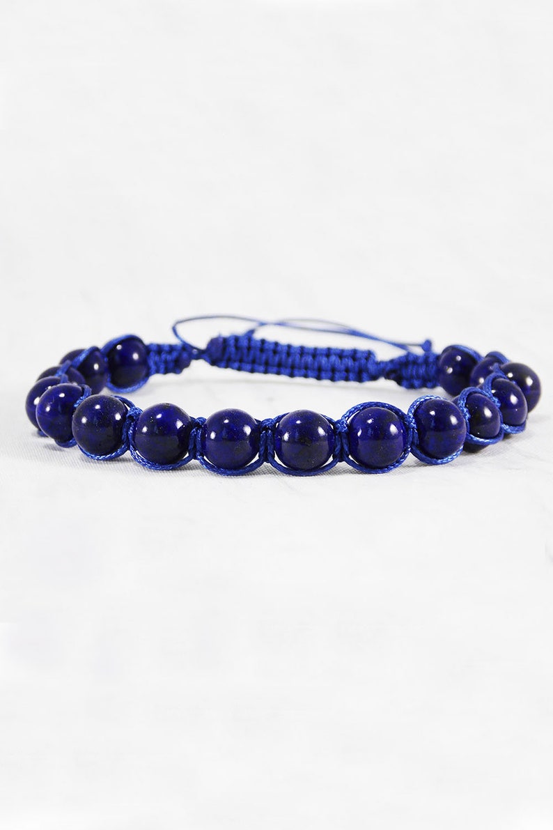 May include: A blue bracelet with dark blue gemstone beads and a blue cord.