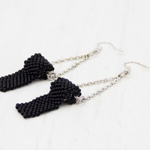 May include: A pair of black beaded earrings with silver chains and hooks. The beads are small and tightly woven, creating a textured look.