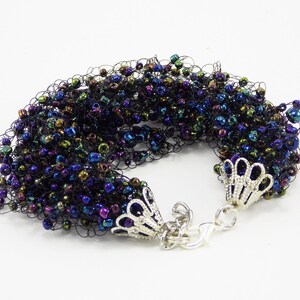 May include: A black crocheted bracelet with iridescent beads and silver clasps.