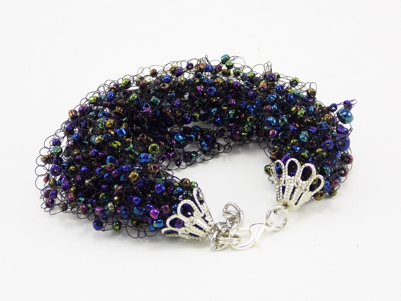 May include: A black crocheted bracelet with iridescent beads and silver clasps.