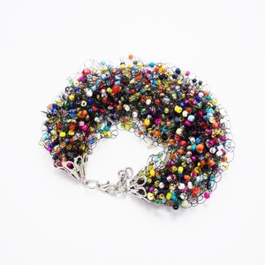 May include: A colorful beaded bracelet with a black crocheted design. The bracelet has a silver clasp.