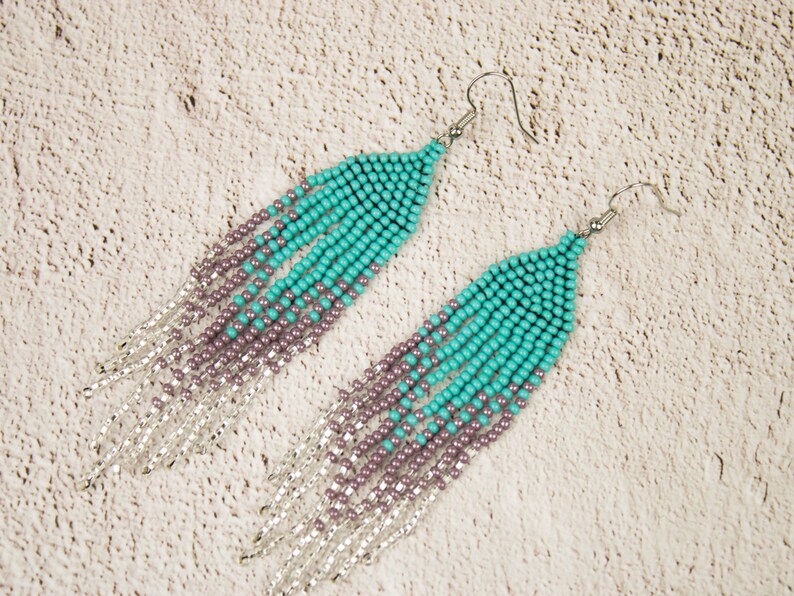 May include: A pair of long, beaded earrings with a gradient of turquoise and purple beads. The earrings have silver accents and silver hooks.