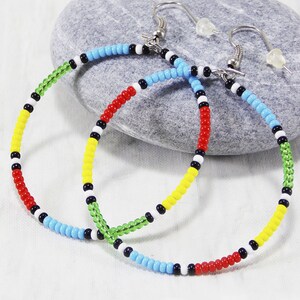 May include: A pair of colorful beaded hoop earrings with red, yellow, green, blue, black, and white beads. The earrings are made with a silver hook.