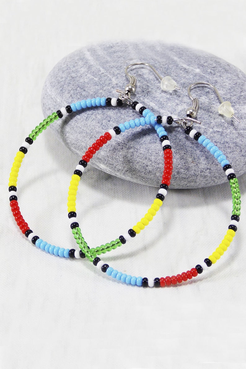 May include: A pair of colorful beaded hoop earrings with red, yellow, green, blue, black, and white beads. The earrings are made with a silver hook.