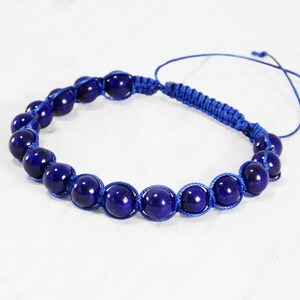 May include: A blue bracelet with dark blue beads and a blue cord.