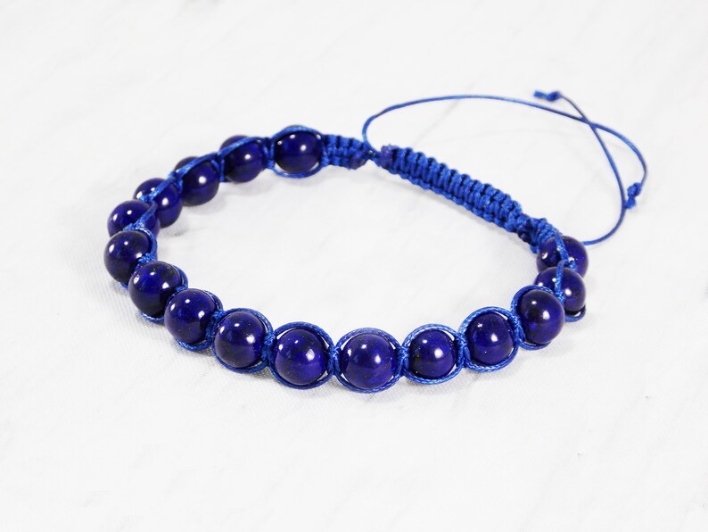May include: A blue bracelet with dark blue beads and a blue cord.