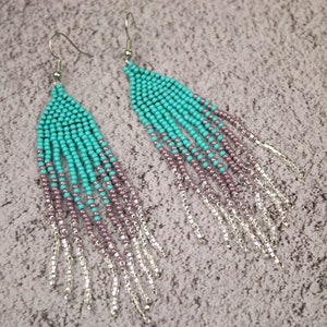 May include: A pair of long, turquoise and purple beaded earrings with silver chain fringe.