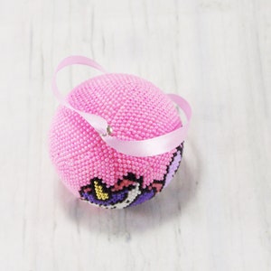 May include: Pink beaded ornament with a unicorn design and a pink ribbon loop.