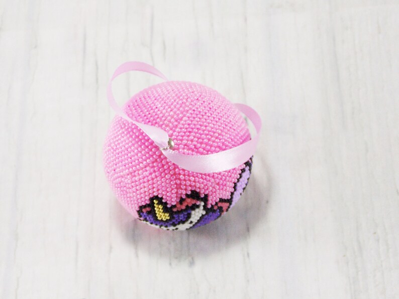 May include: Pink beaded ornament with a unicorn design and a pink ribbon loop.