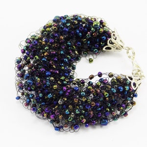 May include: A black crocheted bracelet with iridescent beads. The bracelet has silver metal clasps.