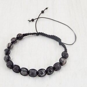 Puede incluir: Un brazalete de cord&oacute;n trenzado negro con cuentas de patr&oacute;n blanco y negro.