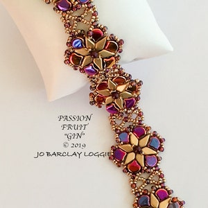 May include: A gold beaded bracelet with a floral design. The beads are in shades of purple, red, gold, and brown. The bracelet is made with seed beads and features a clasp closure. The text "PASSION FRUIT "GIN" © 2019 JO BARCLAY LOGGIE" is visible on the white background.