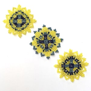 May include: Three beaded suncatchers with a yellow, gray, and black color scheme. The suncatchers are circular and have a geometric design.