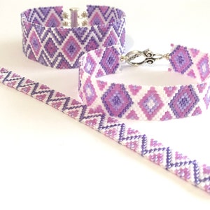 May include: Two beaded bracelets with a geometric pattern in shades of purple and white. The bracelets are made with small seed beads and have a silver clasp.