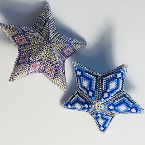 May include: Two beaded star ornaments, one silver with purple and pink accents, and one blue with white accents.