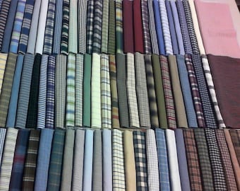 Puede incluir: Una colección de numerosos rollos de tela dispuestos en filas, con una gran variedad de patrones que incluyen cuadros, rayas, vichy y colores sólidos en tonos de azul, verde, rojo, marrón, gris, blanco y rosa, exhibidos lado a lado.
