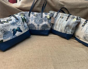 May include: Four tote bags with dark blue bases and dark blue straps. The first bag features blue butterflies and text. The second bag has a blue damask pattern. The third bag displays vertical stripes. The fourth bag shows vintage postal stamps.