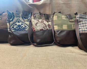 May include: A row of five crossbody bags featuring dark brown leather bases and various fabric tops. The patterns include brown plaid, blue and cream damask, red and cream paisley, olive green plaid, and a black, white, and tan checkered design.