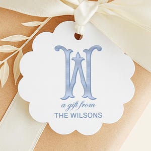 May include: A wrapped gift with a cream-colored ribbon and a scalloped gift tag. The tag features a blue letter "W" and the words "a gift from THE WILSONS". A decorative leaf design is on the gift.