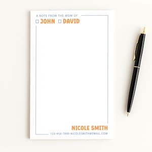 May include: White notepad with blue border and orange text that reads "A note from the mom of John David". Includes contact information and a black pen with gold accents.