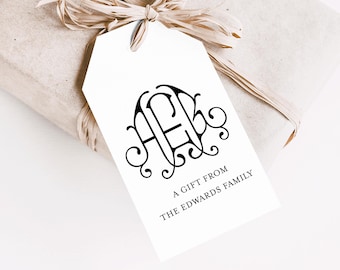 May include: A gift tag with a black monogram and the text "A Gift From The Edwards Family" is tied to a wrapped gift with raffia ribbon. The gift is wrapped in light brown paper.