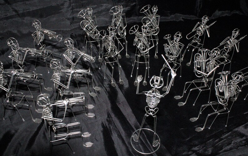 May include: A group of wire skeletons playing musical instruments. The skeletons are arranged in a band formation and are playing a variety of instruments, including a trumpet, a trombone, a tuba, and a drum. The skeletons are all made of wire and are very detailed.