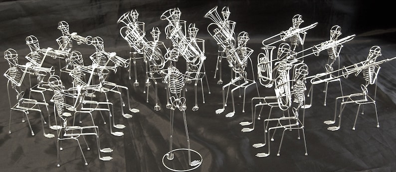 May include: A skeletal band plays musical instruments, including a trombone, trumpet, tuba, and a variety of other instruments. The band members are made of wire and are posed in a realistic playing position.