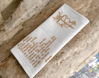 Könnte beinhalten: Ein weißes Gebetstuch aus Leinen mit goldgesticktem Text und einem dekorativen Kreuz- und Taubendesign. Der Text enthält die Worte "Ave Maria" und "Amen". Das Tuch ist rechteckig und scheint neu zu sein.
