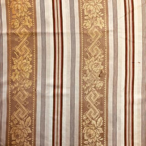 May include: White fabric with brown and red stripes and a repeating pattern of gold floral designs.