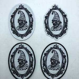 Puede incluir: Cuatro parches en blanco y negro con un retrato de un bufón en un marco ovalado adornado. El bufón lleva un sombrero alto y un cuello con volantes. Dos parches son ovalados y dos tienen una forma ligeramente irregular.