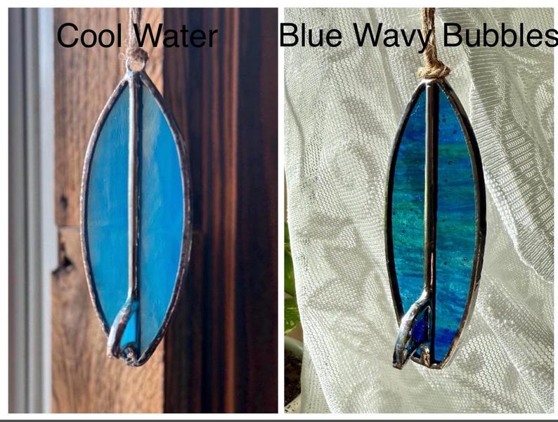 May include: Two stained glass surfboard ornaments. One is solid blue with the text "Cool Water". The other has blue and teal wavy patterns with the text "Blue Wavy Bubbles". Both have a metal frame and are suspended by a string.