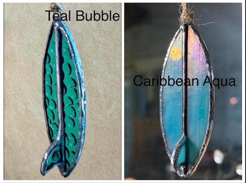 May include: Two stained glass surfboard ornaments. One is teal with a bubble pattern and the text "Teal Bubble". The other is Caribbean blue with a sun design and the text "Caribbean Aqua". Both have a silver border and a twine loop.