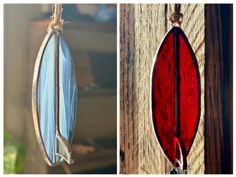 May include: Two stained glass surfboard ornaments. One is blue and white, the other is red. Both have a metal frame and are suspended by a natural fibre cord. The ornaments are designed to resemble surfboards.