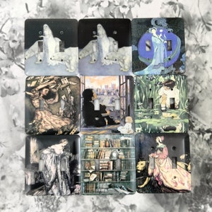 May include: Set of nine light switch covers featuring vintage illustrations. The illustrations include a woman with a crown, a woman with a book, a woman with a dragon, a woman with a cat, a woman with a bird, a woman with a flower, a woman with a star, a woman with a moon, and a woman with a sun.