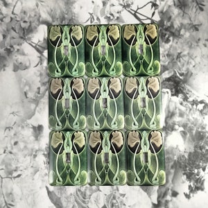 May include: Nine decorative light switch covers with an Art Nouveau design. The covers feature a green background with a floral pattern in shades of green and beige.